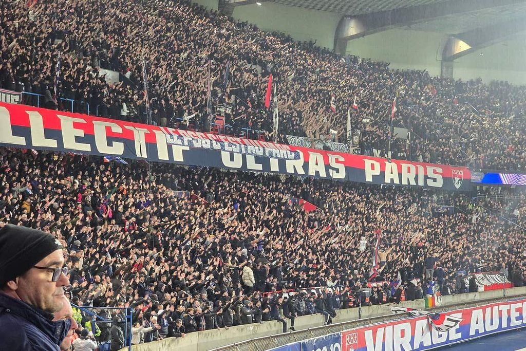 A packed stand at the Parc des Princes with a long red, white and blue banner reading Collectif Ultras Paris.