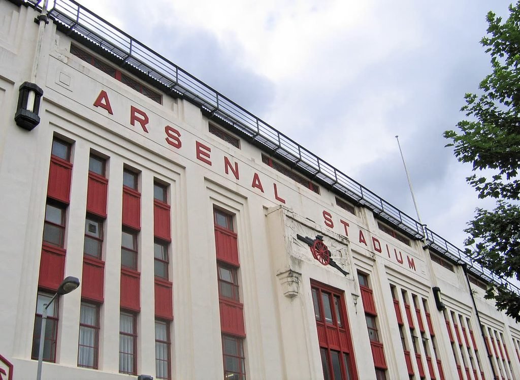 The white Art Deco facade of Highbury's East Stand with ARSENAL STADIUM in red letters.