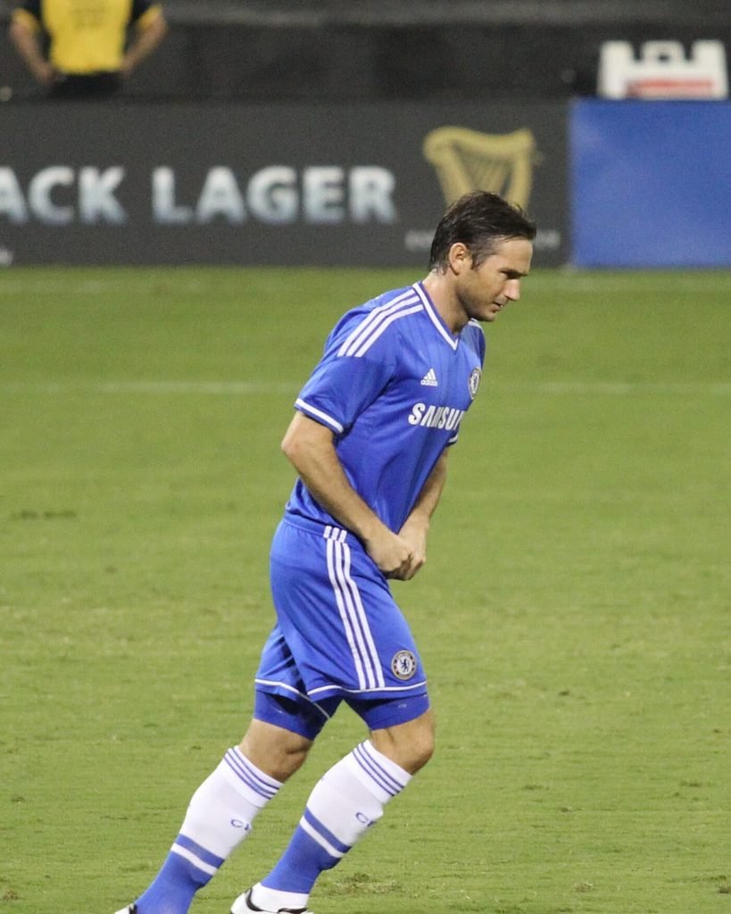 Frank Lampard in a blue Chelsea kit walking on the pitch.