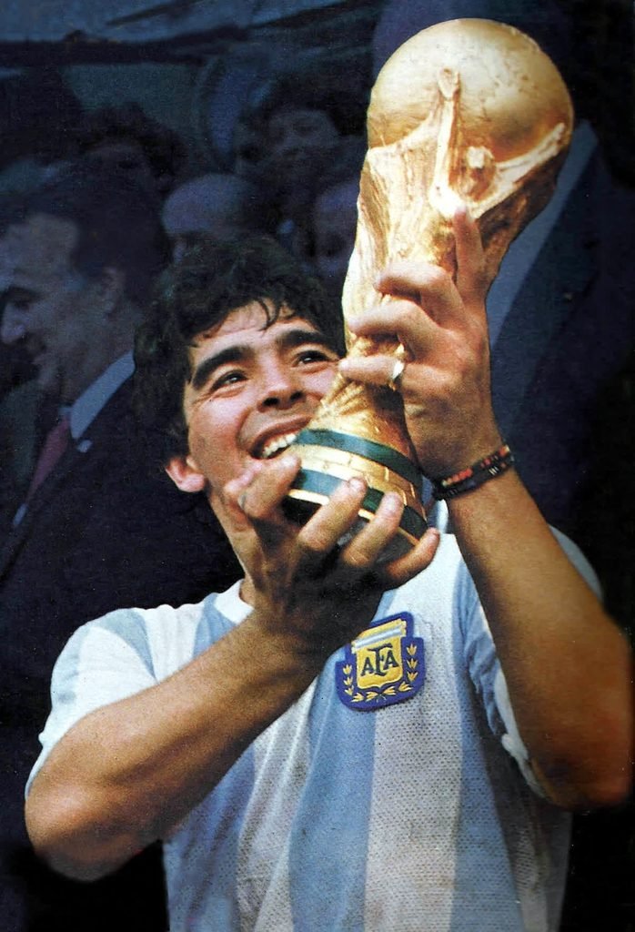 Diego Maradona smiling and holding up the World Cup trophy in 1986.