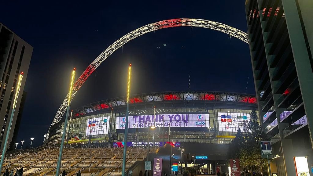 Wembley Stadium lit up at night, its arch glowing, with a big screen reading Thank you for being part of it.